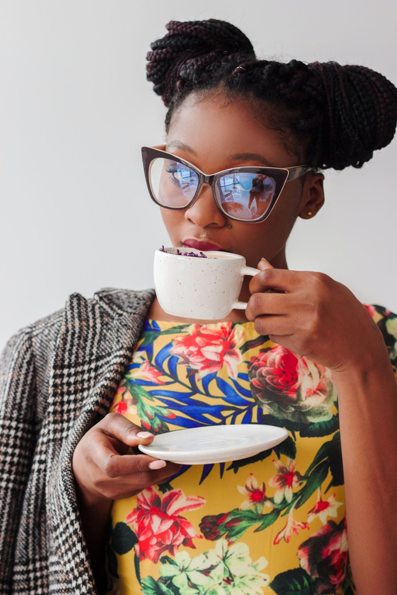 Black woman in funky glasses and colorful dress drinking coffee